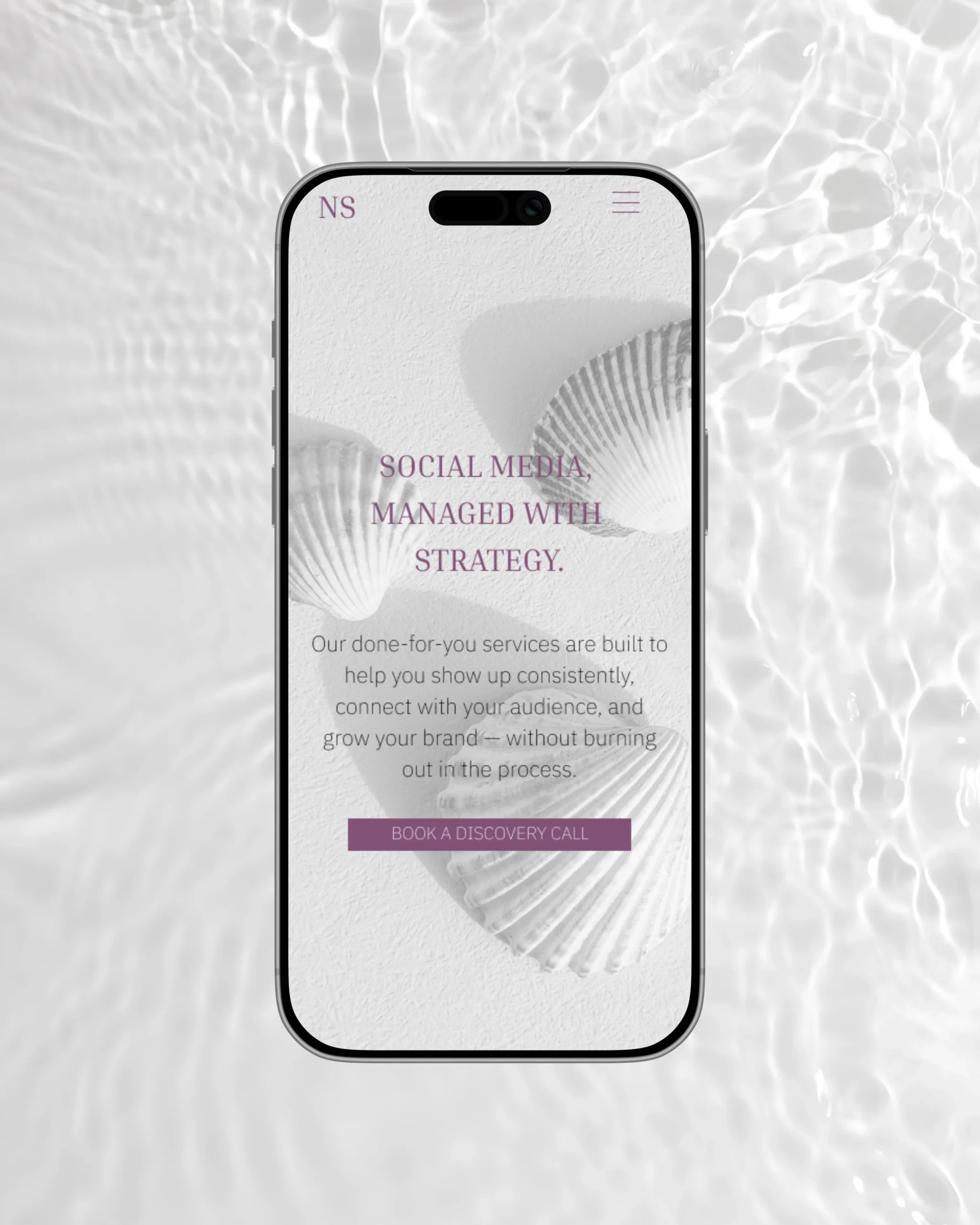Smartphone mockup featuring a website screen for a social media management studio with the headline ‘Social Media, Managed with Strategy’ above a call-to-action button that reads ‘Book a Discovery Call’ – minimalist brand design with seashell imagery for modern service providers.